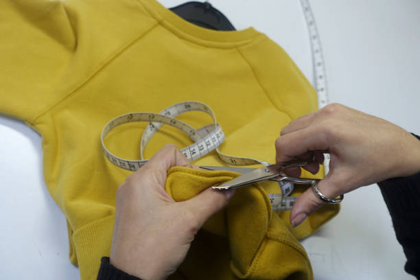 istock Seamstress is cutting drawing for clothing with scissors 864543998