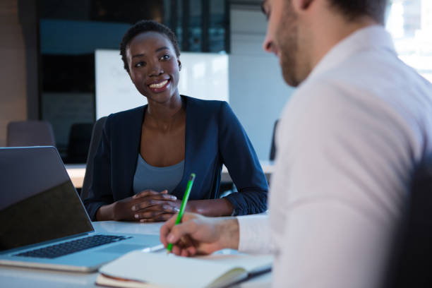 istock Female executive interacting with her colleague at desk 864546560