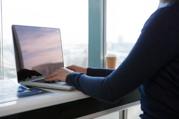 istock Mid section of female executive using laptop at desk 864552142