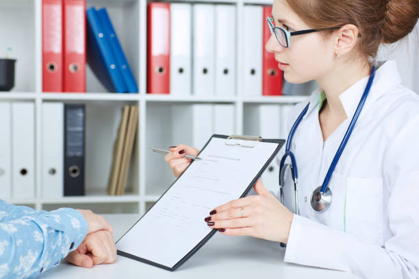istock Young female doctor holding application form while consulting patient. 864553516