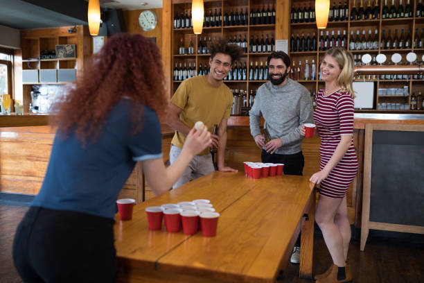 istock Friends playing beer pong on table in bar 864553638