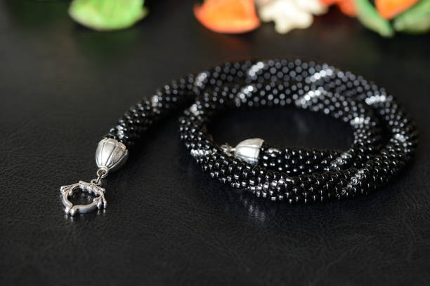 istock Black beaded necklace with silver line on a dark background 864557728