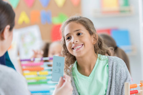 istock Elementary school teacher reviews subtraction flashcards with student 864560454
