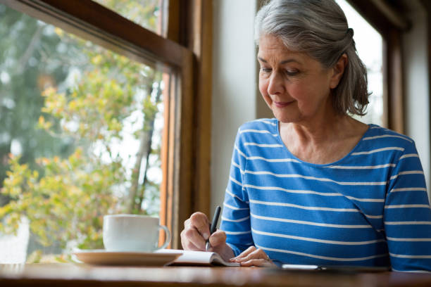 Senior woman writing in a diary stock photo