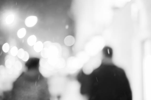 Silhouettes of two friends walking in the night city. High contrast black and white photo.