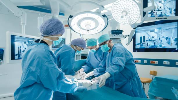 medizinisches team bei chirurgischer operation in hellem modernen operationssaal - operationssaal stock-fotos und bilder