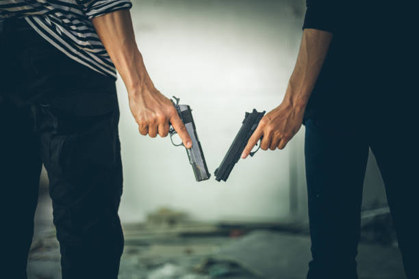 due rapinatori che tenevano una pistola in un edificio abbandonato. foto low key e messa a fuoco selettiva. concetto di criminalità. - thief crime gun hostage foto e immagini stock