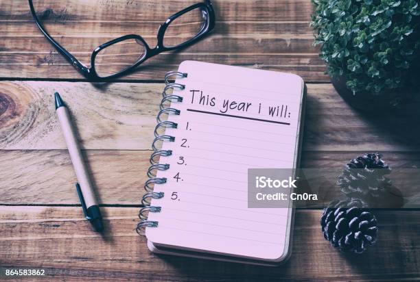 New Year Resolutions List On Notepad On Top Of Wood Desk Stock Photo - Download Image Now