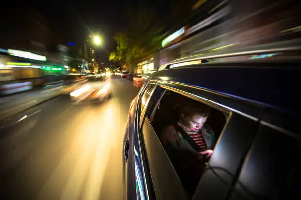 Photo of Woman in Rear of Car Driving Through New York City