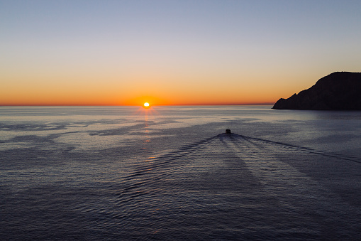 A boat heading into the the sunset in Mediterranean Sea heading off the coast of Vernazza, Cinque Terre, Italy.