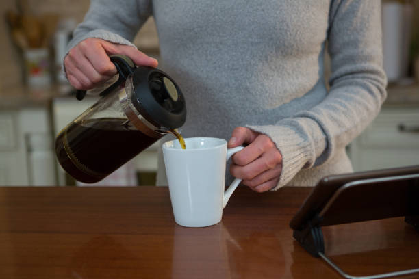 istock Woman pouring coffee into mug in kitchen 864586634