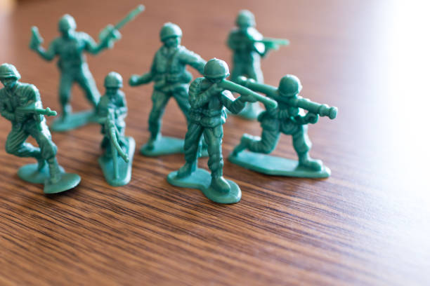 Group of green plastic soldiers on a wooden table prepare to attack. War Action simulated with launchers, bazookas and rifles. stock photo