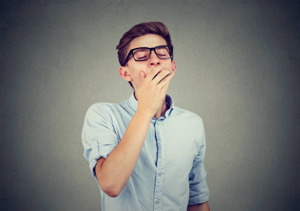 istock Young man yawning with hand over his mouth 864589568