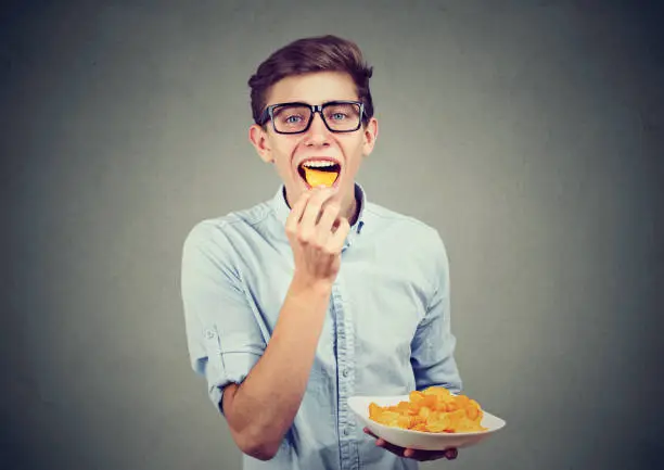 Photo of Young man eating potato chips