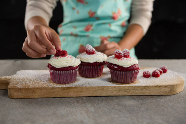 istock Woman arranging raspberries on cupcakes 864595874
