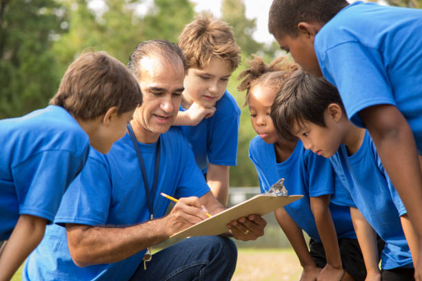 l'allenatore della squadra di calcio spiega il prossimo gioco alla squadra dei suoi figli. - team sport sports team sport community foto e immagini stock