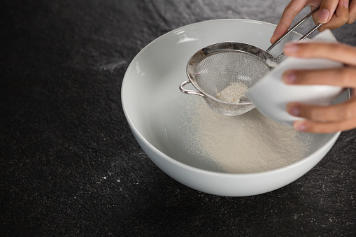 Close-up of woman sieving into the bowl