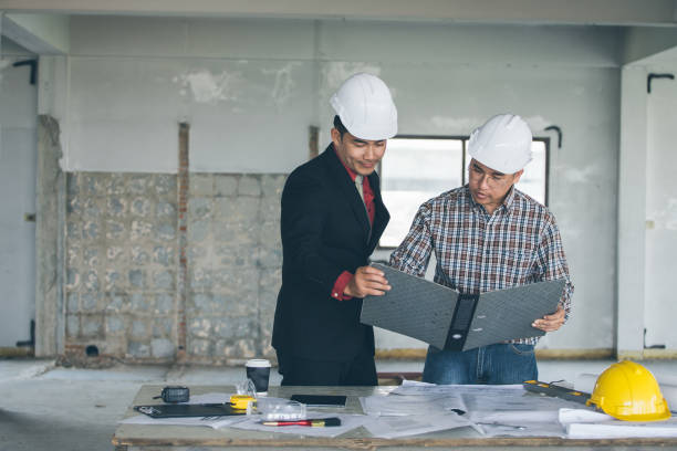 istock Management consulting with engineers working with blueprint and drawing on work table. 864602658