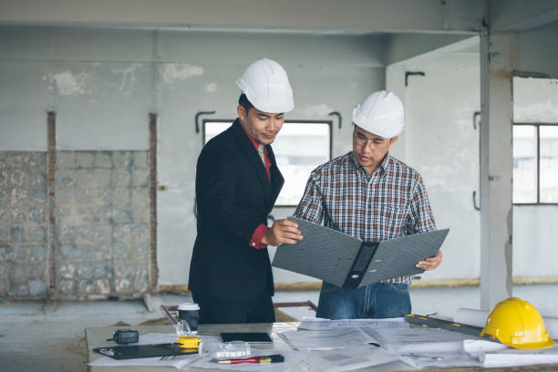 istock Management consulting with engineers working with blueprint and drawing on work table. 864602672