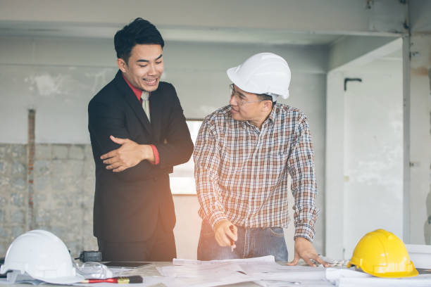 istock Management consulting with engineers working with blueprint and drawing on work table. 864603266