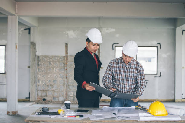 istock Management consulting with engineers working with blueprint and drawing on work table. 864603358