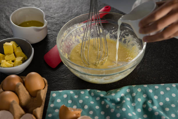istock Woman adding milk to beaten eggs in a bowl 864603750