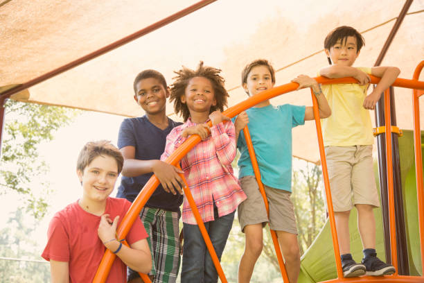 wieloetniczna grupa uczniów bawiących się na szkolnym placu zabaw. - child jungle gym playground laughing zdjęcia i obrazy z banku zdjęć