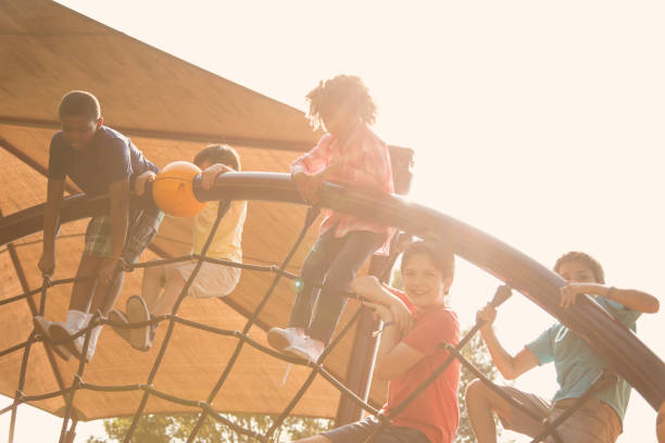 wieloetniczna grupa uczniów bawiących się na szkolnym placu zabaw. - child jungle gym playground laughing zdjęcia i obrazy z banku zdjęć