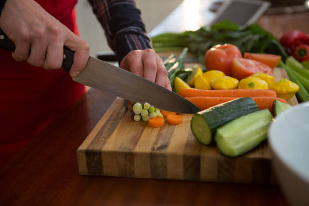 istock Mid section of woman cutting vegetable in kitchen 864604426
