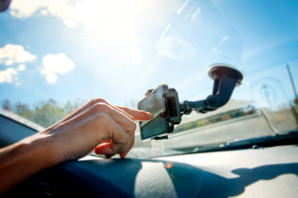 young man using a smpartphone while driving a car closeup of a young caucasian man using a smartphone as a GPS mounted in a holder stuck in the windscreen of a car car pooling photos stock pictures, royalty-free photos & images