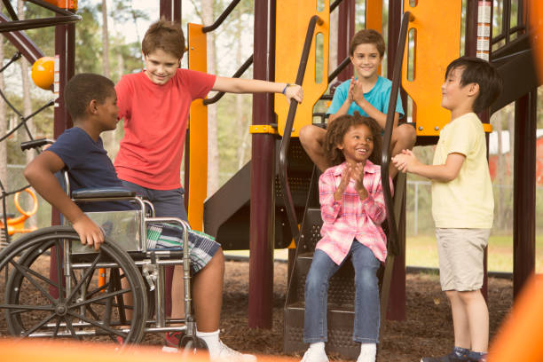 wieloetniczna grupa uczniów na szkolnym placu zabaw, jeden wózek inwalidzki. - child jungle gym playground laughing zdjęcia i obrazy z banku zdjęć