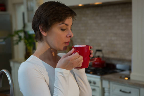 istock Woman having hot drink in kitchen 864607672