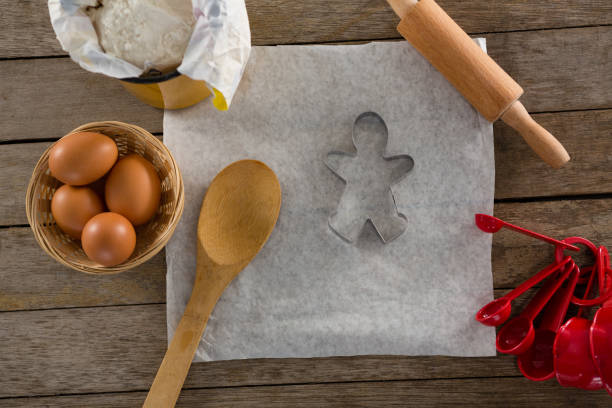 istock Butter paper, flour, rolling pin cookie cutter and eggs kept over a wooden table 864613136