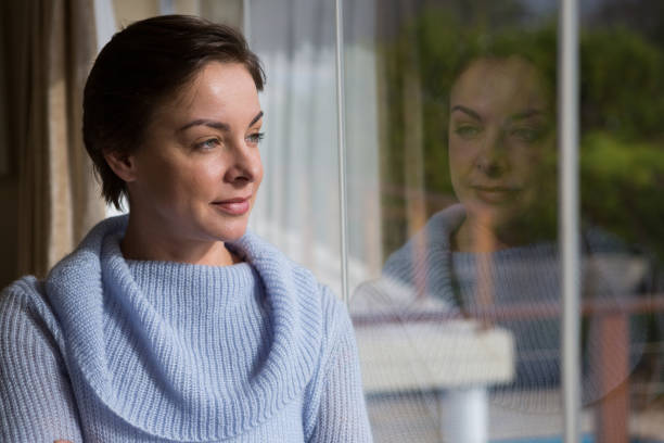 istock Thoughtful woman looking through window 864613642