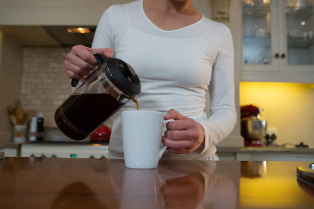 istock Woman pouring coffee into mug in kitchen 864614266