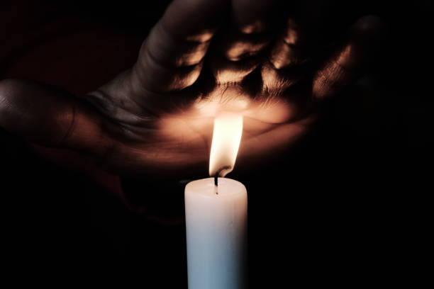 istock Human hand warmed up by a candle in night 864615398
