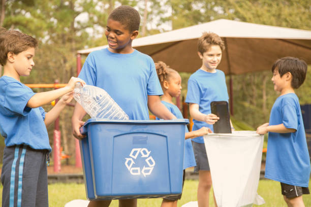 Multi-ethnic group of school children recycling at park. Multi-ethnic group of school children recycling and picking up trash at their local park, school playground.  The sports team of volunteers is happy to clean up their community. garbage bin photos stock pictures, royalty-free photos & images