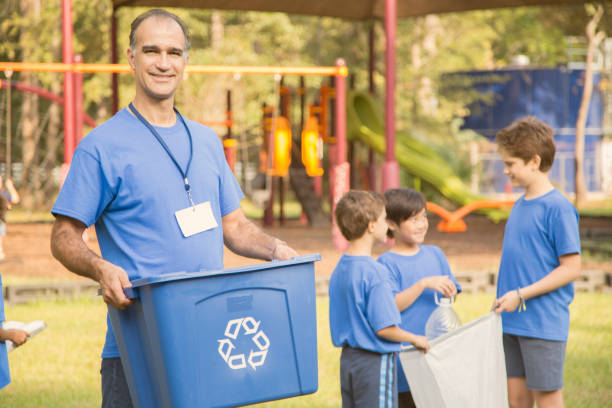 multi-ethnic group of school children, coach recycling at park. - wasting time imagens e fotografias de stock