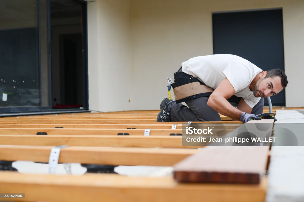 charpentier de beau jeune homme installer une terrasse extérieure de plancher de bois dans la construction neuve, maison - Photo de Terrasse en bois libre de droits