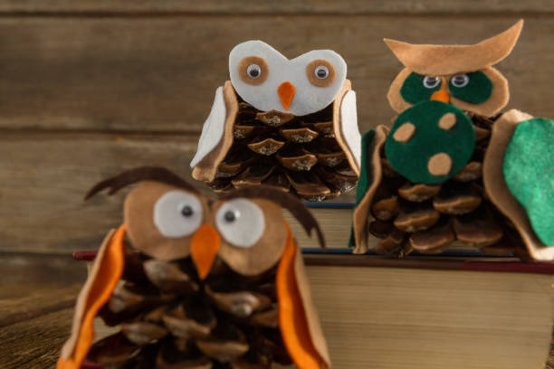 istock Owl decorated with pine cone and book stack on wooden table 864646014