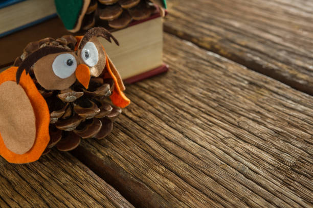 istock Owl decorated with pine cone and book stack on wooden table 864646806