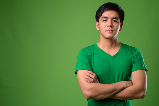 Portrait of young Filipino man against green background