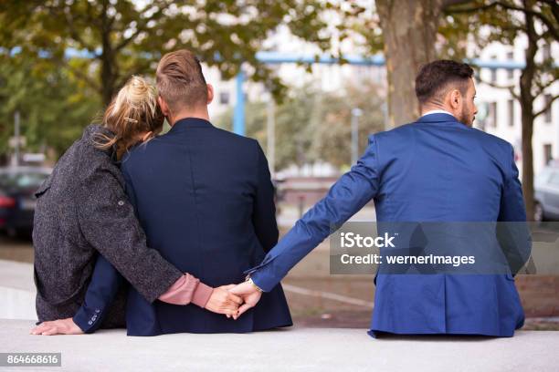 Couple Hugging While The Woman Holding Hands With Another Man Stock Photo - Download Image Now