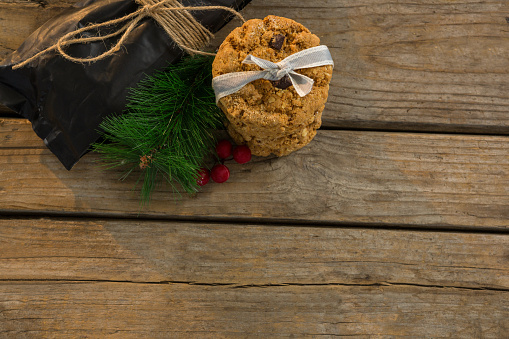 High angle view of cookies with pine needles and cheeries by plastic bag on table