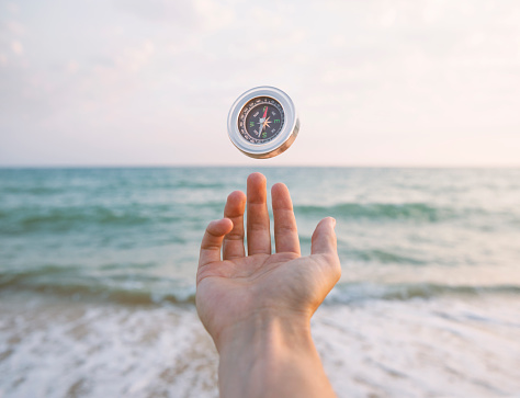 Hand with Compass with sea background.