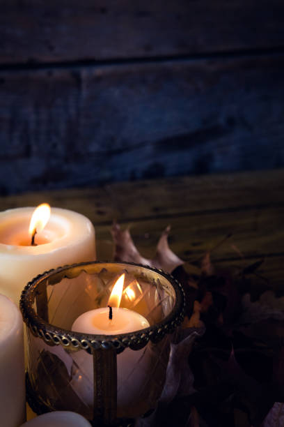 istock Lit candles and dry leaves on table 864685048