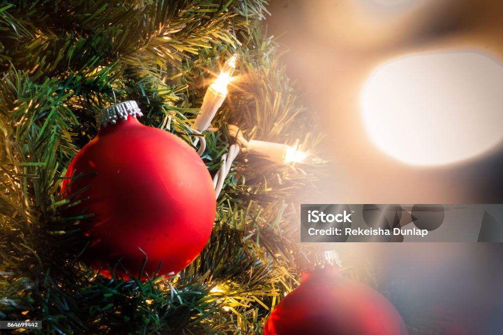 A close-up of a red Christmas ornament A christmas ball on a christmas treen behind christmas lights Christmas Ornament Stock Photo
