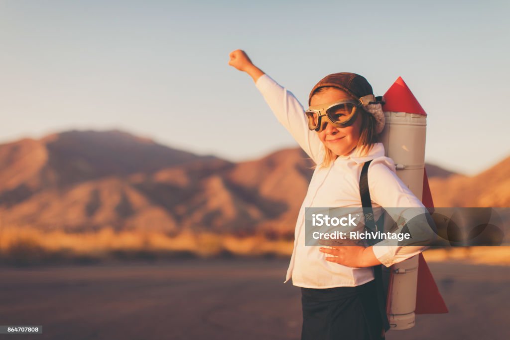 Young Business Girl with Rocket Pack A young girl businesswoman or student dressed in business attire looks to the distance while wearing a rocket strapped to her back and a flying cap and goggles. She is standing on a country road among the mountains of Utah, USA. She is confident in her abilities to lead her business and obtain her goals. Child Stock Photo