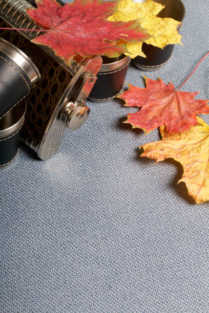 istock A jar lying on a gray fabric and metal glasses covered in leather. They are strewn with fallen autumn leaves of different colors. 864713070