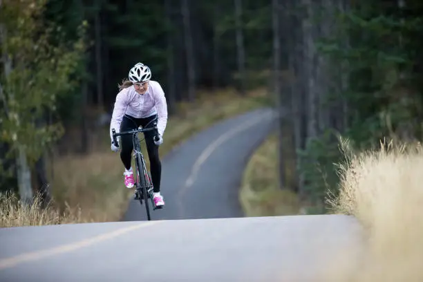 She is riding a road bike and wearing warm clothing.